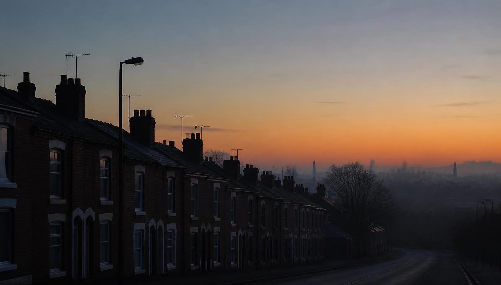 A Birmingham street of terraced houses at dawn, the sky turning gold above the rooftops